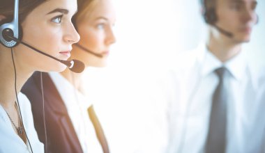 Kulaklıklı, güler yüzlü iş kadını müşterilere danışıyor. Sunny Office 'de çalışan çeşitli telefon operatörleri. Çağrı merkezi ve iş adamları kavramı.