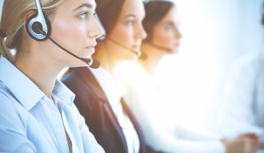 Kulaklıklı, güler yüzlü iş kadını müşterilere danışıyor. Sunny Office 'de çalışan çeşitli telefon operatörleri. Çağrı merkezi ve iş adamları kavramı.