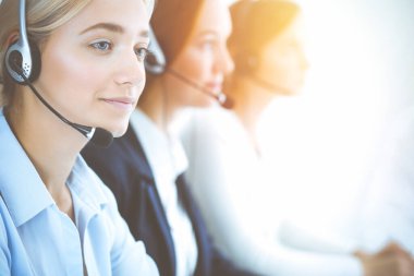 Kulaklıklı, güler yüzlü iş kadını müşterilere danışıyor. Sunny Office 'de çalışan çeşitli telefon operatörleri. Çağrı merkezi ve iş adamları kavramı.