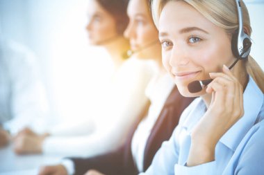 Kulaklıklı, güler yüzlü iş kadını müşterilere danışıyor. Sunny Office 'de çalışan çeşitli telefon operatörleri. Çağrı merkezi ve iş adamları kavramı.