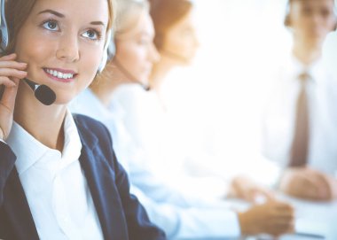 Kulaklıklı, güler yüzlü iş kadını müşterilere danışıyor. Sunny Office 'de çalışan çeşitli telefon operatörleri. Çağrı merkezi ve iş adamları kavramı.