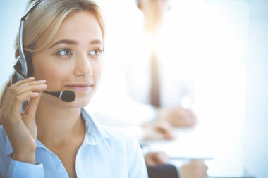 Kulaklıklı, güler yüzlü iş kadını müşterilere danışıyor. Sunny Office 'de çalışan çeşitli telefon operatörleri. Çağrı merkezi ve iş adamları kavramı.