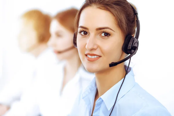 Exploitanten van callcenters. Focus op mooie zakelijke vrouw met behulp van headset in zonnig kantoor — Stockfoto