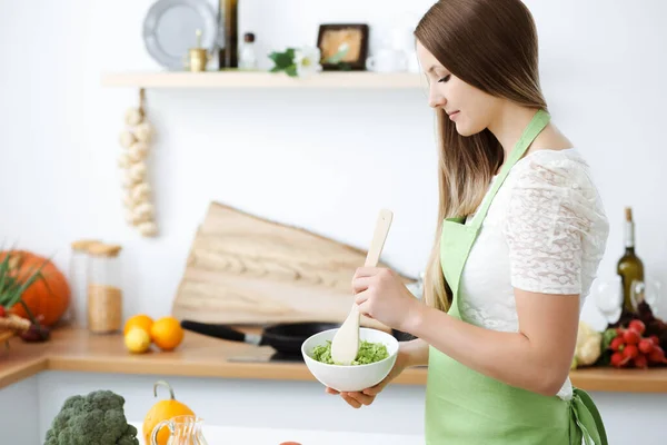 Mulher bonita vestida de avental está cozinhando refeição na cozinha. dona de casa cortando salada vegan fresco — Fotografia de Stock