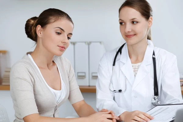 El médico y el paciente están sentados y discutiendo los resultados del examen de salud en el consultorio clínico. Salud, medicina y conceptos de buenas noticias — Foto de Stock