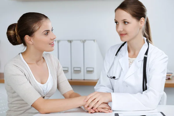 Dokter en patiënt zitten en bespreken gezondheidsonderzoek resultaten in kliniek kantoor. Gezondheidszorg, geneeskunde en goede nieuwsconcepten — Stockfoto