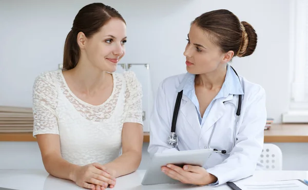 Doctor and patient are sitting and discussing health examination results while using tablet computer. Health care, medicine and good news concepts — Stock Photo, Image