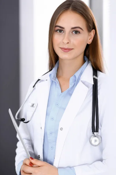 病院の窓の近くに立っている間、タブレットコンピュータを使用して医師の女性。仕事中の幸せな医者。医療・ヘルスケアの概念 — ストック写真