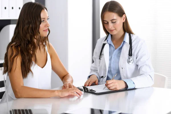 Médico y paciente feliz hablando mientras está sentado en el escritorio. El médico o terapeuta discute el estilo de vida saludable. Concepto de atención de salud, medicina y servicio al paciente — Foto de Stock