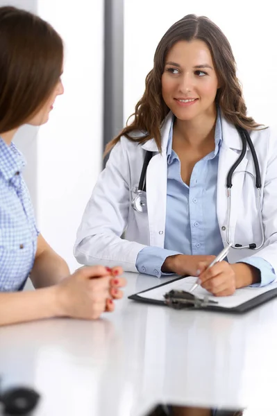 Médico y paciente feliz hablando mientras está sentado en el escritorio. El médico o terapeuta discute el estilo de vida saludable. Concepto de atención de salud, medicina y servicio al paciente — Foto de Stock