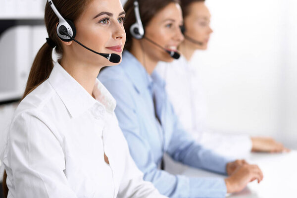 Call center. Group of operators at work. Focus on beautiful business woman in headset