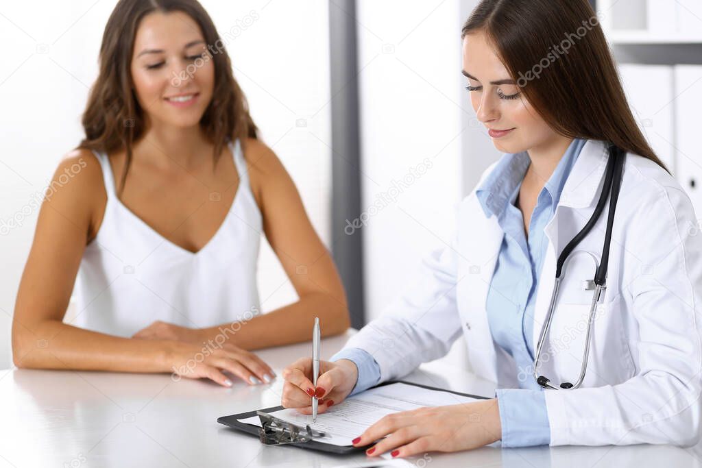 Doctor and happy patient talking while sitting at the desk. The physician or therapist discussing healthy lifestyle. Health care, medicine and patient service concept