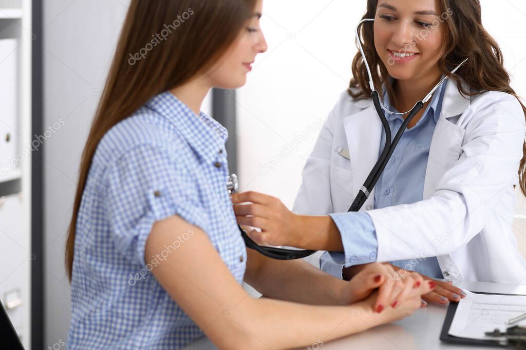 Doctor with a stethoscope in the hand examining her female patient. Health care, cardiology and medicine concepts