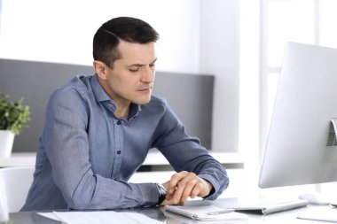 Modern ofiste bilgisayarla çalışan bir iş adamı. İş yerindeki erkek girişimcinin ya da şirket müdürünün vesikalığı. İş konsepti