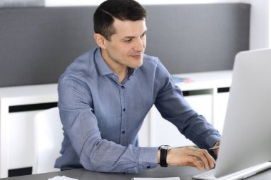 Modern ofiste bilgisayarla çalışan bir iş adamı. İş yerindeki erkek girişimcinin ya da şirket müdürünün vesikalığı. İş konsepti