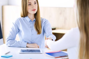 İş kadını, iş yerinde bayan meslektaşı veya müşterisiyle tokalaşırken kafasından vurulmuş. İş adamlarının günlük beyaz kıyafet tarzı. Denetim, vergi veya avukat kavramı