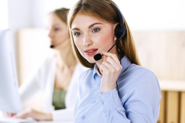 Çağrı merkezi operatörünün portresi. Kulaklık takmış bir grup insan müşterilere yardım etmeye hazır. İş konsepti