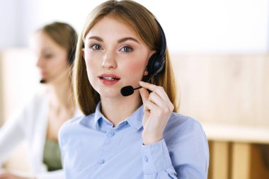 Çağrı merkezi operatörünün portresi. Kulaklık takmış bir grup insan müşterilere yardım etmeye hazır. İş konsepti