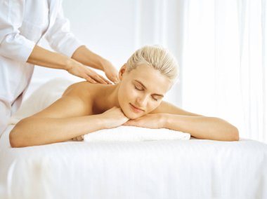 Güzel sarışın kadın kapalı gözlerle sırt masajından hoşlanıyor. Spa salonu konsepti