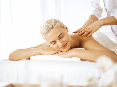 Güzel sarışın kadın kapalı gözlerle sırt masajından hoşlanıyor. Spa salonu konsepti
