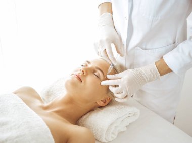 Güzellik uzmanı elleri şırıngayla kadın yüzüne güzellik prosedürü uyguluyor. Kozmetik tıp ve cerrahi, güzellik enjeksiyonları konsepti