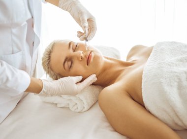 Güzellik uzmanı elleri şırıngayla kadın yüzüne güzellik prosedürü uyguluyor. Kozmetik tıp ve cerrahi, güzellik enjeksiyonları konsepti