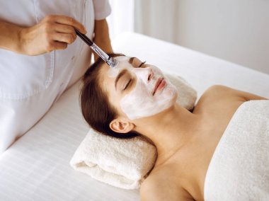 Güzel esmer kadın kapalı gözlerle kozmetik maske takmaktan zevk alıyor. Tıp ve kaplıca merkezi kavramlarında rahatlatıcı tedavi