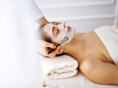 Güzel esmer kadın kapalı gözlerle kozmetik maske takmaktan zevk alıyor. Tıp ve kaplıca merkezi kavramlarında rahatlatıcı tedavi