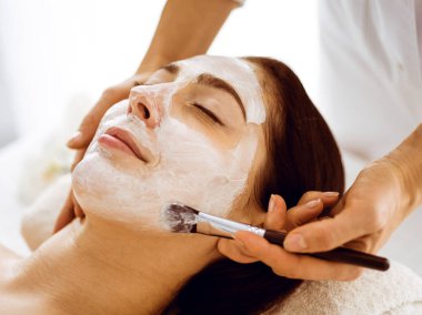 Güzel esmer kadın kapalı gözlerle kozmetik maske takmaktan zevk alıyor. Tıp ve kaplıca merkezi kavramlarında rahatlatıcı tedavi