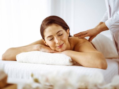 Güzel esmer kadın gözleri kapalı sırt masajından hoşlanıyor. Spa ve tıp konsepti