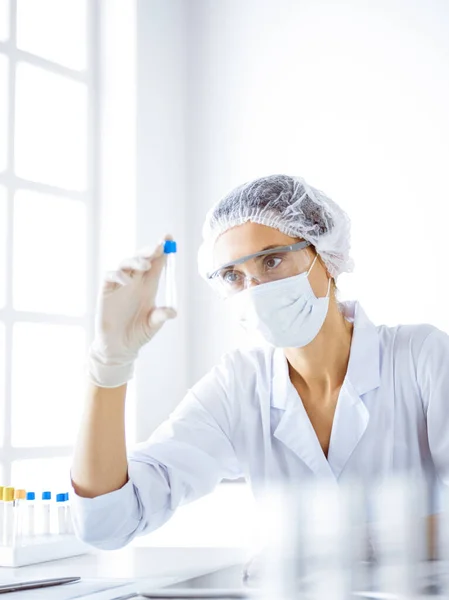 Professzionális női tudós védőszemüvegben, kémcsövet kutatva reagensekkel a laboratóriumban. Az orvostudomány és a tudományos kutatás fogalma — Stock Fotó