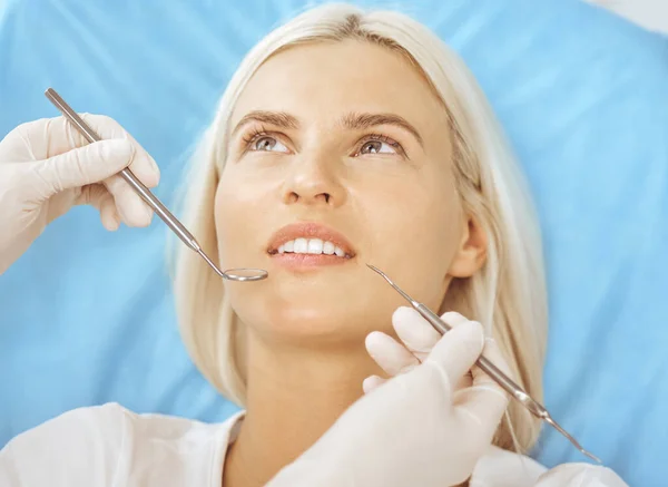 Uśmiechnięta blondynka badana przez dentystę w klinice dentystycznej. Zdrowe zęby i koncepcja medycyny — Zdjęcie stockowe
