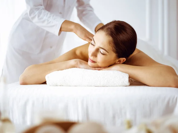 Bella donna bruna godendo massaggio alla schiena con gli occhi chiusi. Concetto di spa e medicina — Foto Stock