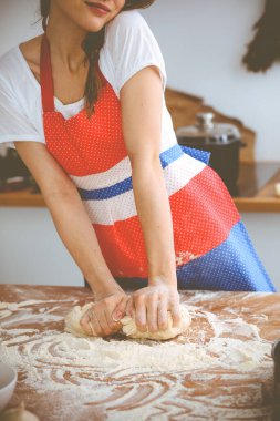 Genç esmer kadın mutfakta pizza ya da el yapımı makarna pişiriyor. Ev hanımı ahşap masada hamur hazırlıyor. Diyet, gıda ve sağlık konsepti