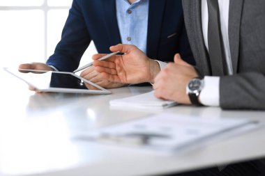 Tablet bilgisayar kullanan iki bilinmeyen işadamı ya da ortak modern ofiste görüşülen sorular, yakın çekim. Pazarlık yapan ya da beyin fırtınası yapan bir grup yönetici. Takım çalışması, ortaklık ve