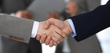 İş adamları toplantıdan ya da pazarlıktan sonra iş arkadaşlarıyla el sıkışıyorlar. Yakın plan. Modern ofisteki bir grup tanınmamış iş adamı ve kadın. Takım çalışması, ortaklık ve tokalaşma