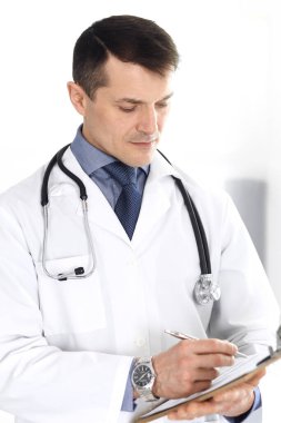 Doktor, ilaç kayıtlarını doldurmak için pano kullanıyor. Klinikte mükemmel bir tıbbi hizmet. Hastanede çalışan bir doktor. Tıp ve sağlık hizmetleri kavramları