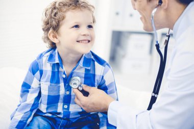 Doktor ve sabırlı çocuk. Doktor küçük çocuğu muayene ediyor. Kliniğe düzenli tıbbi ziyaret. İlaç ve sağlık hizmetleri kavramı