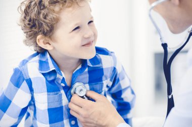 Doktor ve sabırlı çocuk. Doktor küçük çocuğu muayene ediyor. Kliniğe düzenli tıbbi ziyaret. İlaç ve sağlık hizmetleri kavramı