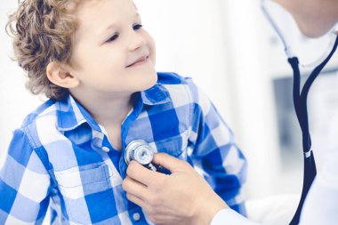 Doktor ve sabırlı çocuk. Doktor küçük çocuğu muayene ediyor. Kliniğe düzenli tıbbi ziyaret. İlaç ve sağlık hizmetleri kavramı