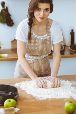 Genç esmer kadın mutfakta pizza ya da el yapımı makarna pişiriyor. Ev hanımı ahşap masada hamur hazırlıyor. Diyet, gıda ve sağlık konsepti