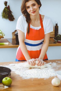 Genç esmer kadın mutfakta pizza ya da el yapımı makarna pişiriyor. Ev hanımı ahşap masada hamur hazırlıyor. Diyet, gıda ve sağlık konsepti