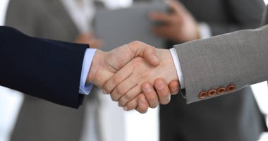 İş adamları toplantıdan ya da pazarlıktan sonra iş arkadaşlarıyla el sıkışıyorlar. Yakın plan. Modern ofisteki bir grup tanınmamış iş adamı ve kadın. Takım çalışması, ortaklık ve tokalaşma
