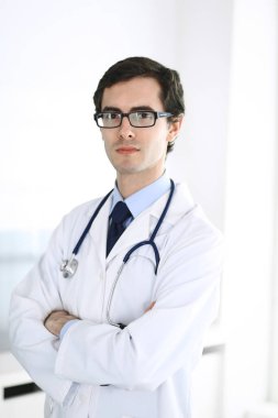 Doktor adam kollarını kavuşturarak dimdik ayakta duruyor. Klinikte mükemmel bir tıbbi hizmet. Tıp ve sağlık sektöründe mutlu bir gelecek