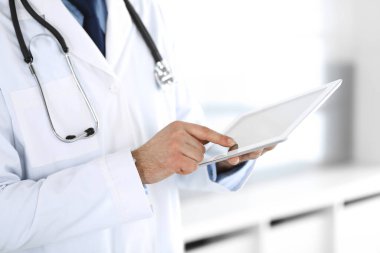 Doktor, ağ araştırması ya da sanal hastalık tedavisi için tablet bilgisayar kullanıyor. Eller yakın çekim. Klinikte mükemmel bir tıbbi hizmet. Modern tıp, tıbbi veri ve sağlık hizmetleri kavramları. Ayarlanmış