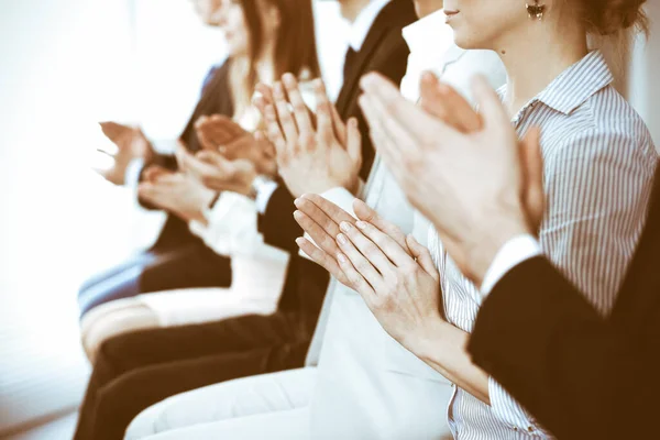 Business people clapping and applause at meeting or conference, close-up of hands. Group of unknown businessmen and women in modern white office. Success teamwork or corporate coaching concept