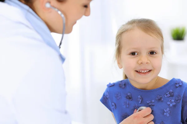 Doutor examinando uma menina por estetoscópio. Paciente de criança sorridente feliz em inspeção médica habitual. Conceitos de medicina e saúde — Fotografia de Stock