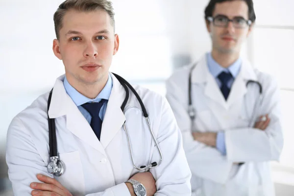 Doktor adam arka planda meslektaşıyla birlikte ayakta duruyor. Bir grup doktor. Klinikte mükemmel bir tıbbi hizmet. Tıp ve sağlık hizmetleri kavramları — Stok fotoğraf