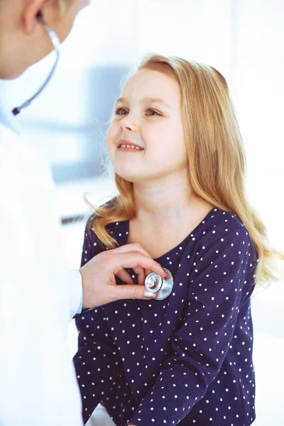 Médico examinando a un niño paciente por estetoscopio. Linda niña en la cita con el médico. Concepto de medicina. Foto tonificada —  Fotos de Stock