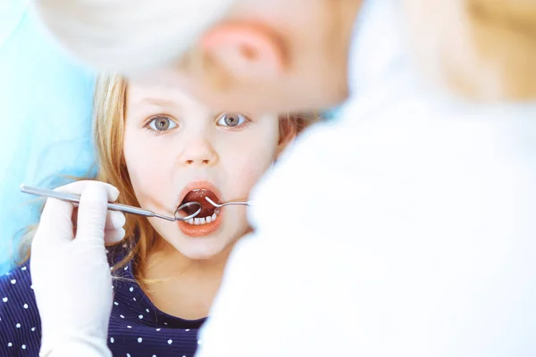 Mała dziewczynka siedzi na krześle dentystycznym z otwartymi ustami podczas kontroli doustnej, podczas gdy lekarz. Odwiedzam gabinet dentystyczny. Koncepcja medyczna. Uszkodzone zdjęcie — Zdjęcie stockowe